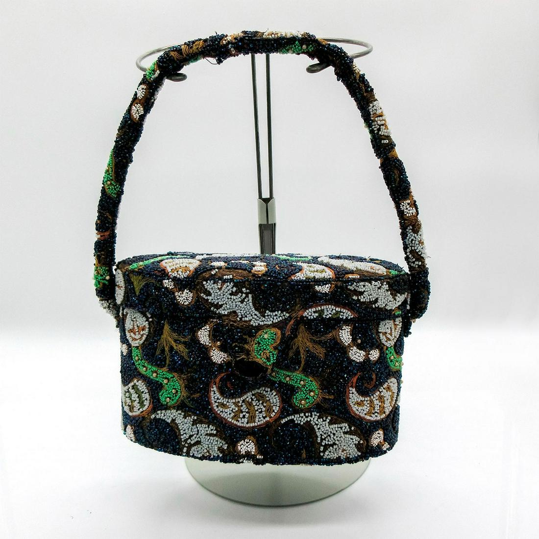 Vintage DeLill Navy Tone Oval Paisley Leaf Design Purse Box: Has exterior handle for carrying, and 2 interior pockets. Lid is attached with 2 straps. Sparkly beadwork colors range from white to brown to blue. Has button snap closure. DeLill printed on interior