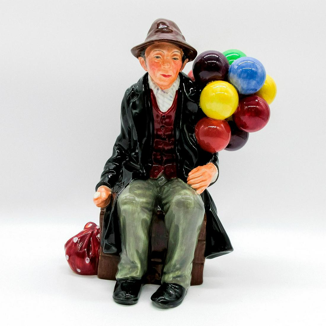 Balloon Man HN1954 - Royal Doulton Figurine: Balloon Characters series. Seated elderly man with balloons. Stamp to base. Hat reglued. Artist: Leslie Harradine Issued: 1940 - 2009 Dimensions: 7.25"H Manufacturer: Royal Doulton Country of Origin: 
