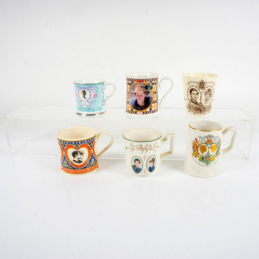 6pc Assortment of Royal Family Commemorative Mugs: 5 pottery memorabilia mugs honoring Prince Charles and Princess Diana. 1 gilded gold bone china Prince Harry mug. Manufactures marks on the base. Largest: 3.5"H x 3"D. This item has its original box.