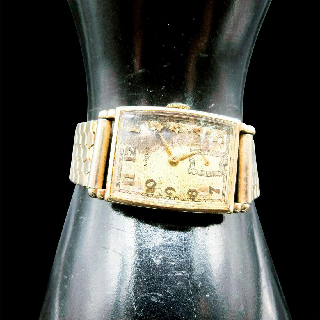 Vintage Hamilton 10K Gold Watch: Art deco style dial face with gold tone numbers and hands. Elastic bracelet with stainless steel backing. Has initials CJM and birthdate of previous owner engraved on the back. Hamilton backstamp. 22m