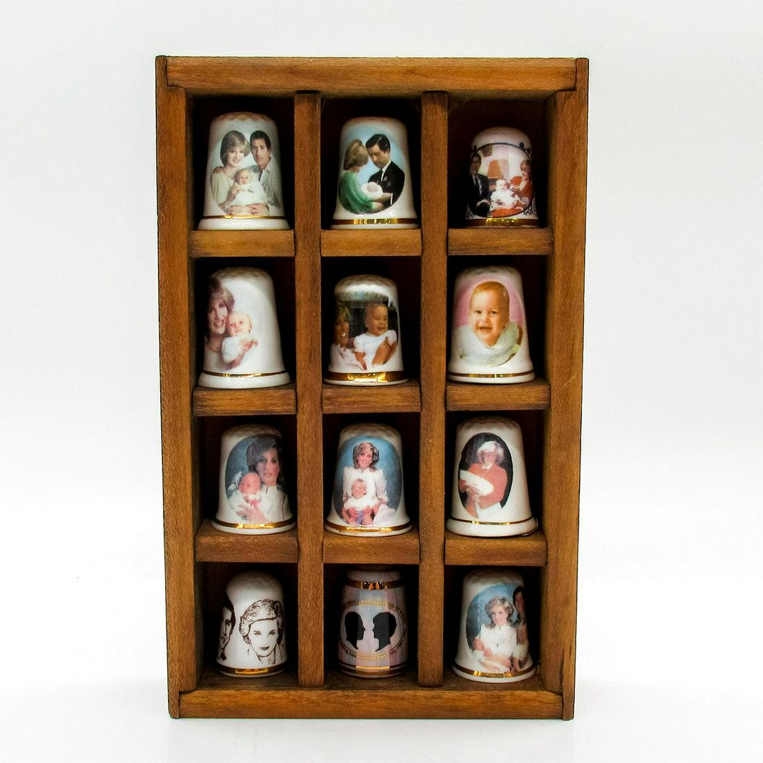 13pc Vintage Collectible Royal Family Thimbles: Bone china thimbles honoring life events of the royal family. Includes births, birthdays, visits, and anniversaries. Twelve thimbles and wooden display box included. 1"H each. 6.25"L x 4"W. Issued: 20