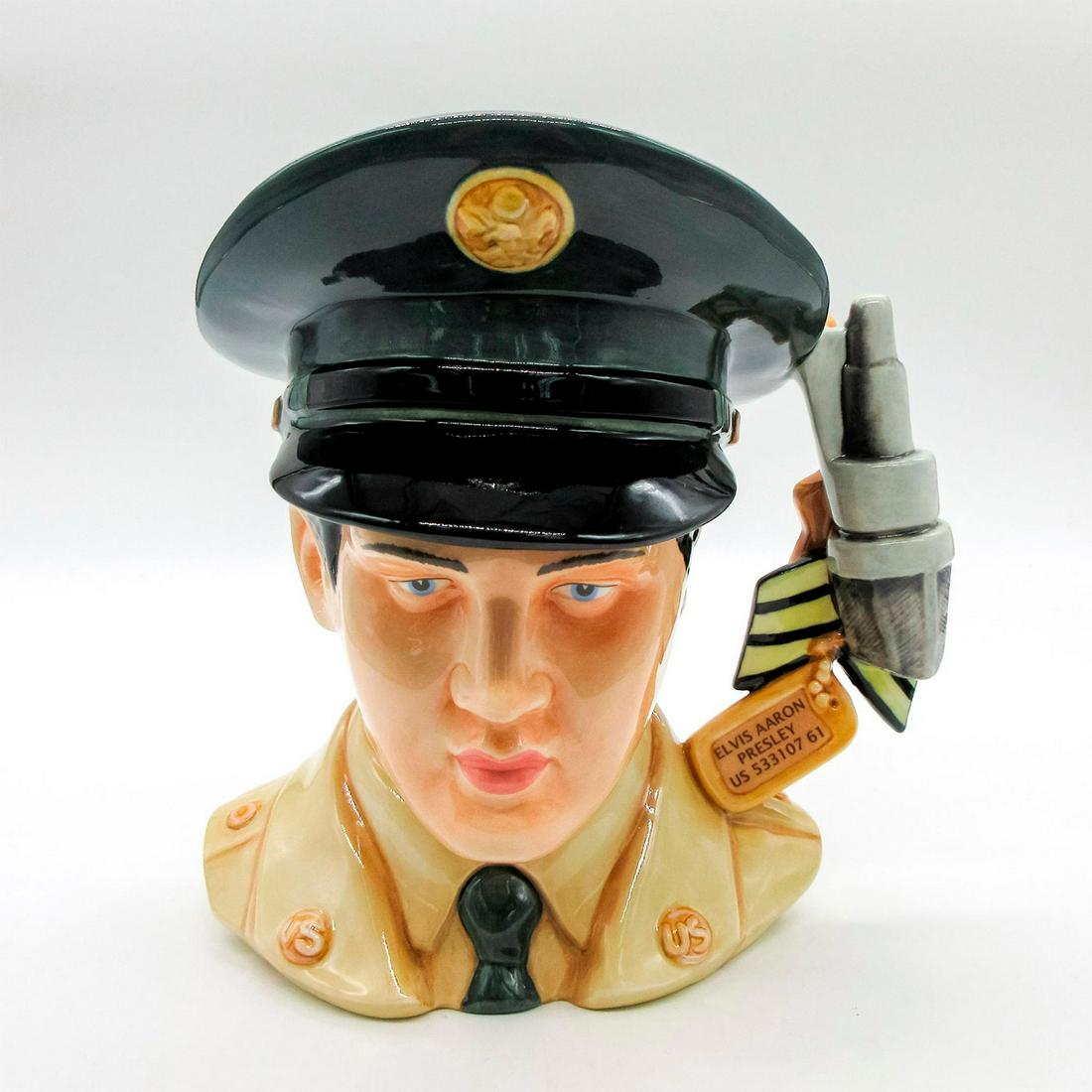Elvis GI Blues EP9 - Large - Royal Doulton Character Jug: Dog tag, Sergeant stripes, microphone, guitar, and medals handle. G.I. Blues (1960) was Elvis' fifth film. The soundtrack album became the top-selling album of his career. Handle represents his two ye
