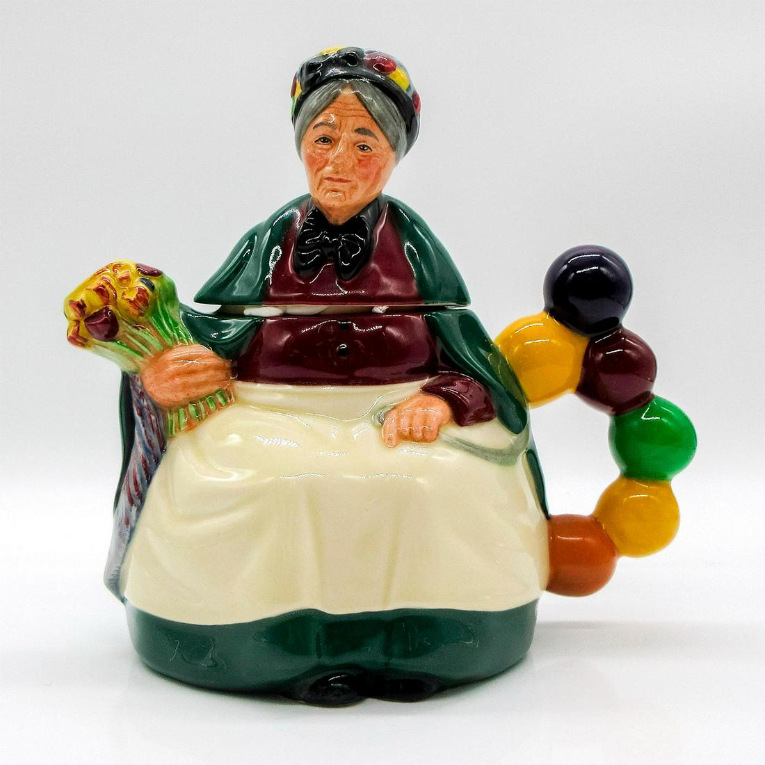 Old Balloon Seller D6854 - Royal Doulton Teapot: Green, white, yellow, and maroon coloration. Royal Doulton backstamp. Artist: William K. Harper Issued: 1989 - 1991 Dimensions: 6.5"H Manufacturer: Royal Doulton Country of Origin: England