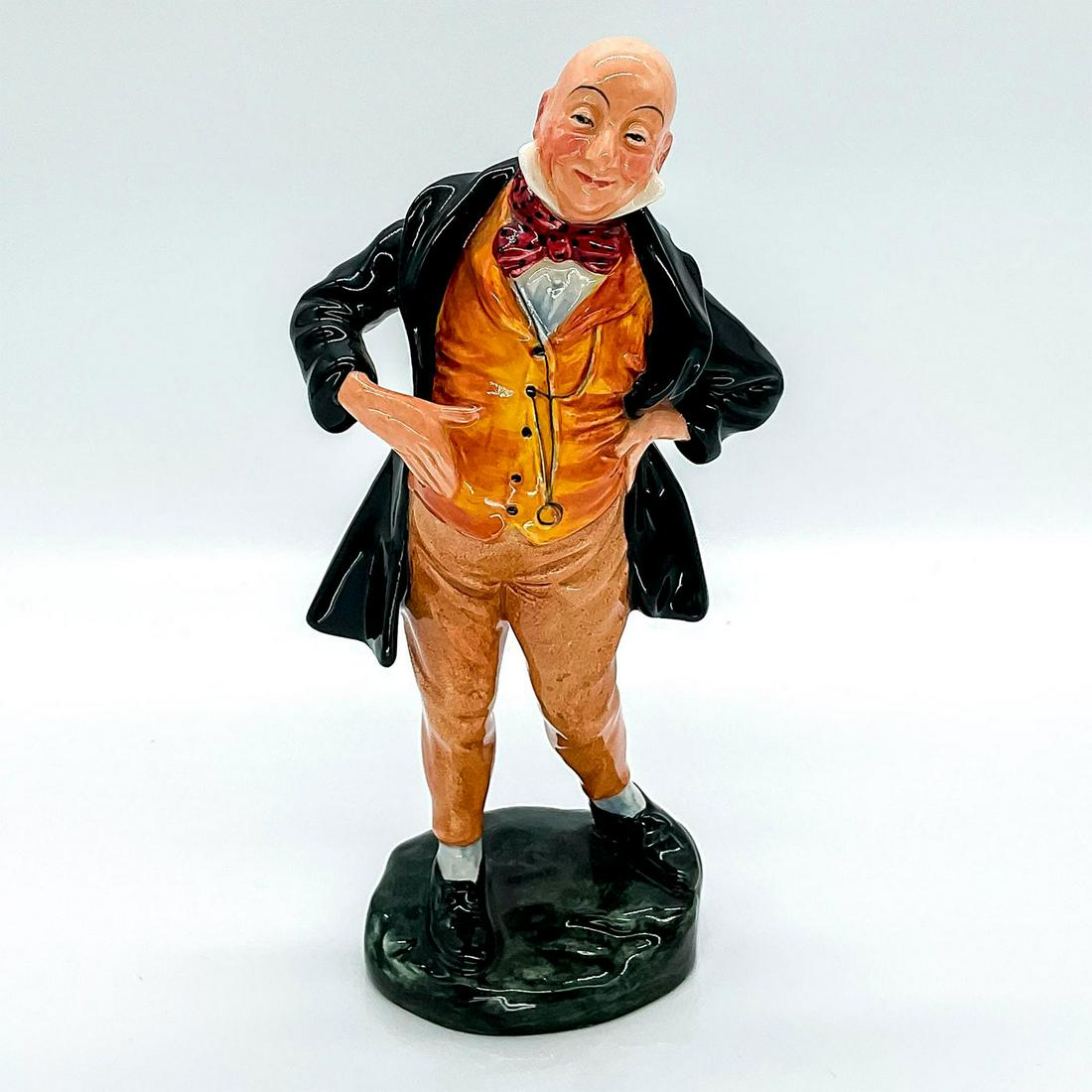 Mr. Micawber HN2097 - Royal Doulton Figure: Part of Charles Dickens series. Depicts a character standing wearing a black coat with a red bow tie and a yellow suit. Royal Doulton backstamp. Artist: Leslie Harradine Issued: 1952 - 1967 Dimensions