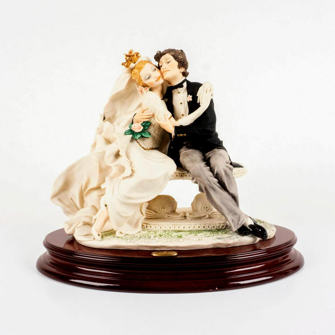 Florence Giuseppe Armani Figurine, Beloved 1319F: Lovely, intricately detailed bride and groom in a loving embrace while sitting on a garden bench. Limited edition number and artists signature on the base of the figure. Stands permanently attached to