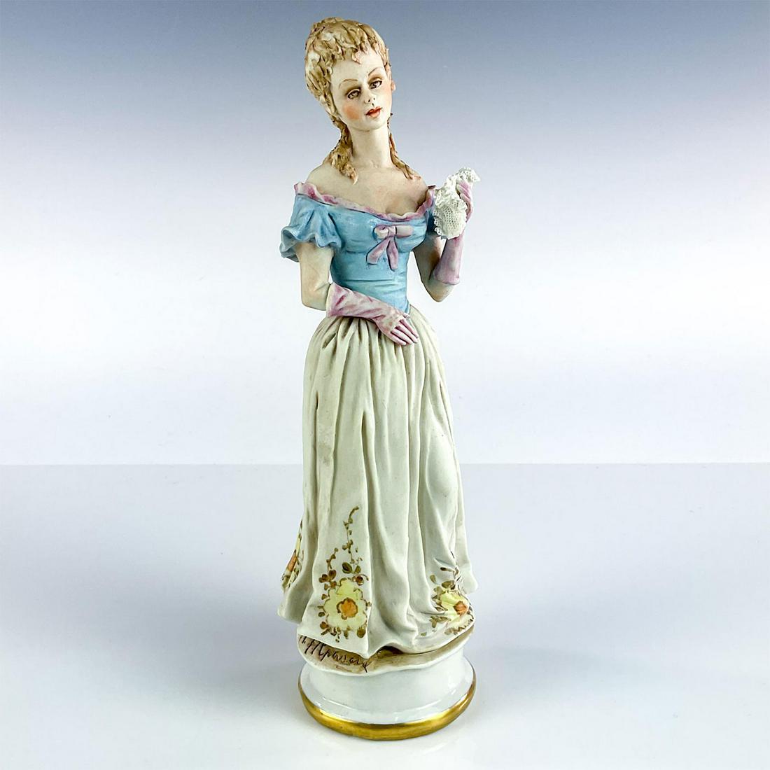 Vintage Capodimonte Figurine, Italian Woman: Ceramic figurine modeled as young woman holding lacy handkerchief in hand. Blue, lavender, yellow, and cream color. Artist signature to base. Capodimonte backstamp. Issued: 20th c. Dimensions: 9"H Man