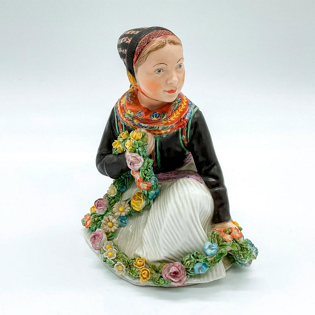 Royal Copenhagen Porcelain Figurine, Amager Girl: Figure of a young Danish girl holding a garland of flowers. 12412; Royal Copenhagen backstamp. Artist: Carl Martin-Hansen Issued: c. 1948 Dimensions: 4"L x 4"W x 5"H Manufacturer: Royal Copenhagen Cou