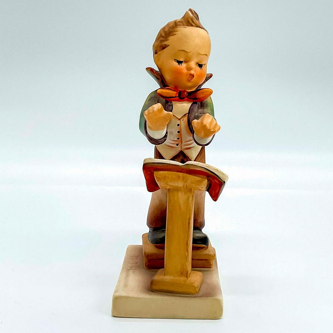 Goebel Hummel Figurine, Band Leader: Porcelain hand painted in matte finish. Goebel backstamp. Impressed M. I. Hummel to square base. Artist: M. I. Hummel Issued: 20th c. Dimensions: 1.75"L x 1.25"W x 5.25"H Manufacturer: Goebel Hummel C