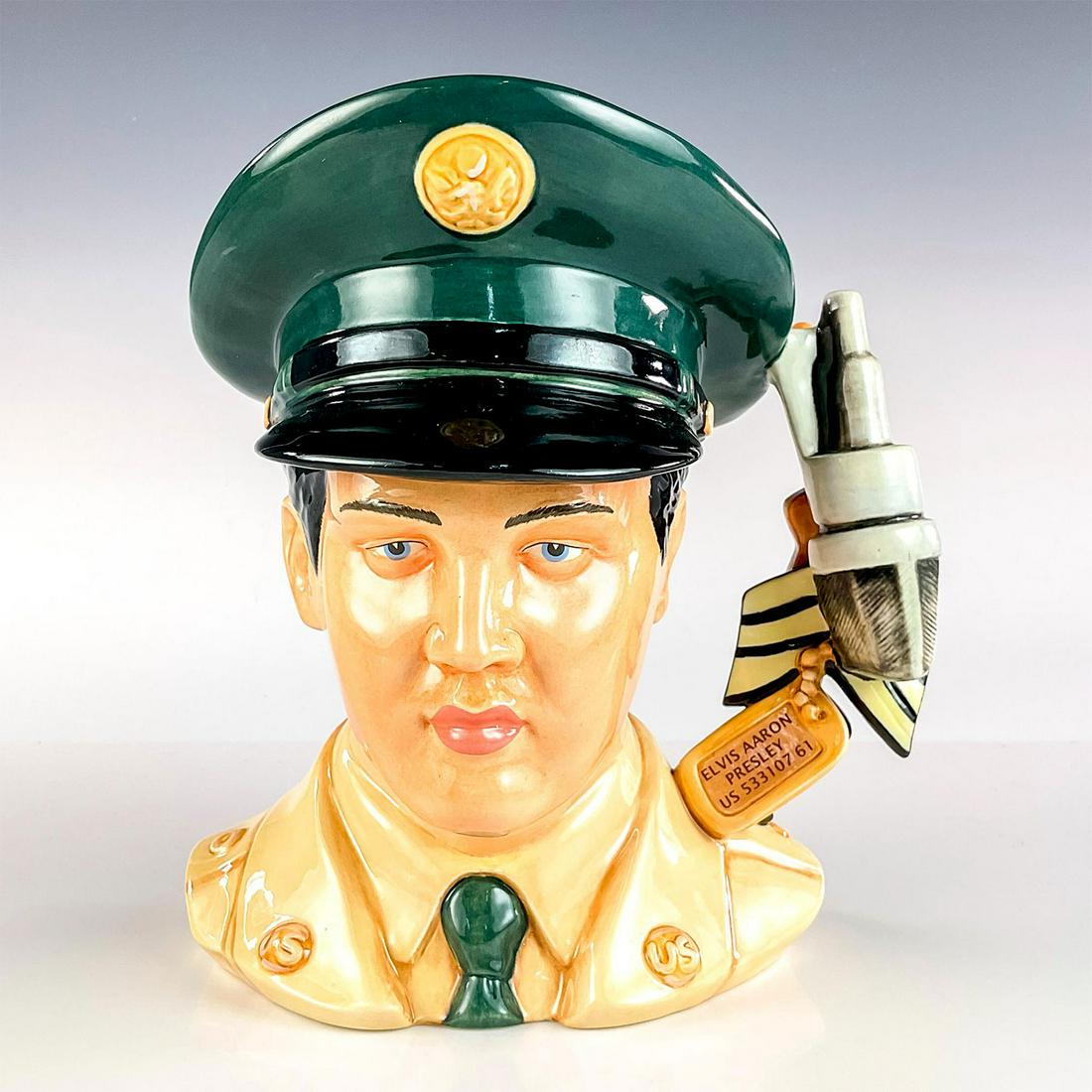 Elvis GI Blues EP9 - Large - Royal Doulton Character Jug: Dog tag, Sergeant stripes, microphone, guitar, and medals handle. G.I. Blues (1960) was Elvis' fifth film. The soundtrack album became the top-selling album of his career. Handle represents his two ye