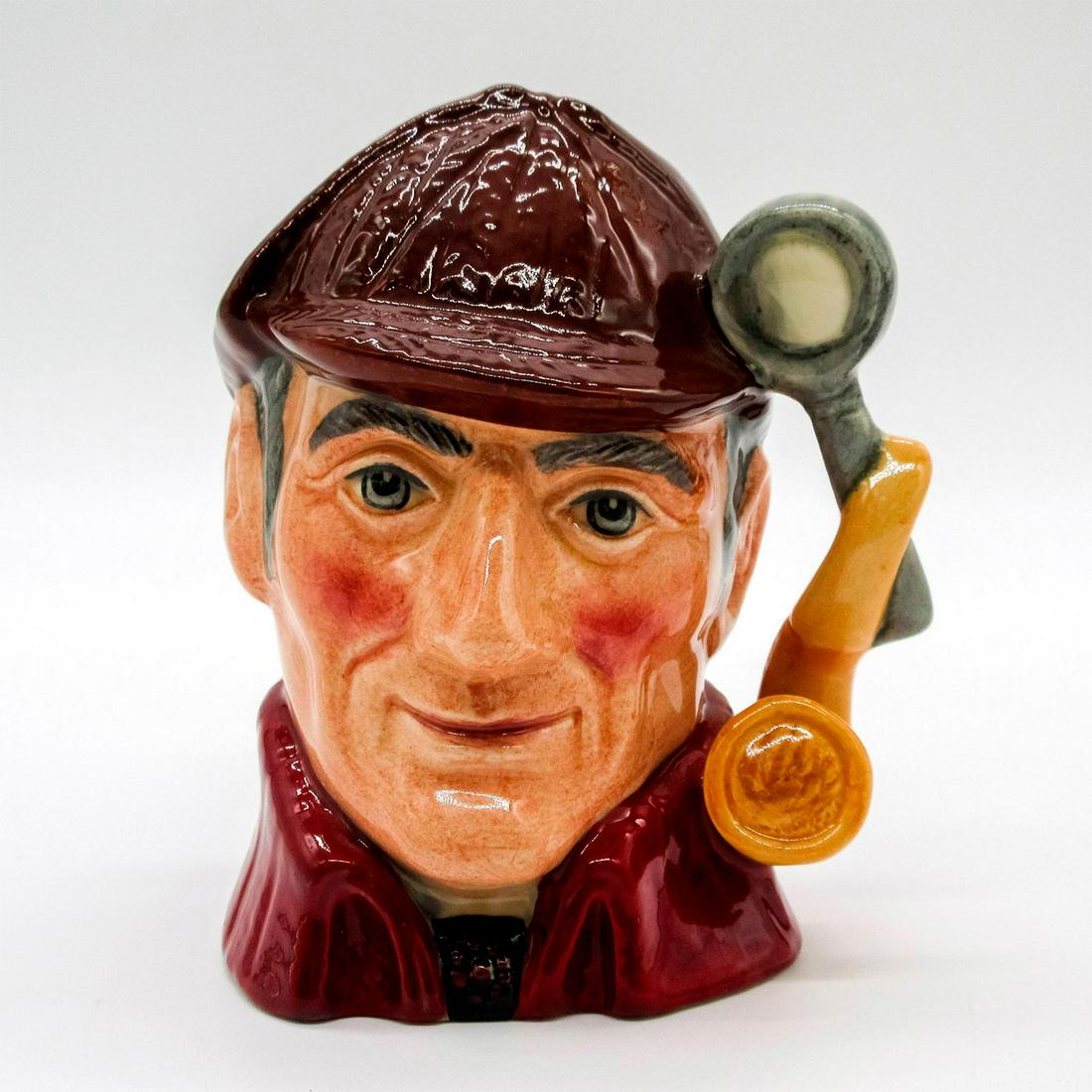 Sleuth D6773 (Colorway) - Small - Royal Doulton Character Jug: Variation Two. Brown deerstalker hat; red cloak. Arthur Conan Doyle (1859 - 1930), an unsuccessful doctor, published the first of his widely popular detective stories in 1887. The amateur sleuth Sherl