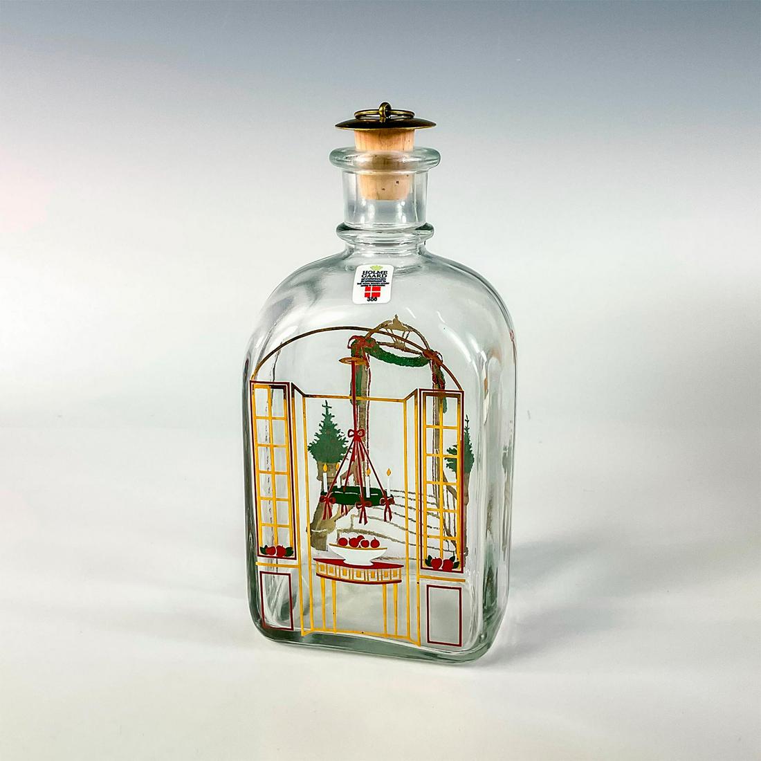 Holmegaard of Copenhagen Christmas Bottle 1986: Decorated glass bottle in a festive Christmas doorway design in green, red and gold. The other side features a candelabra above a table with fruit. Holmegaard affixed label. Includes original cork and