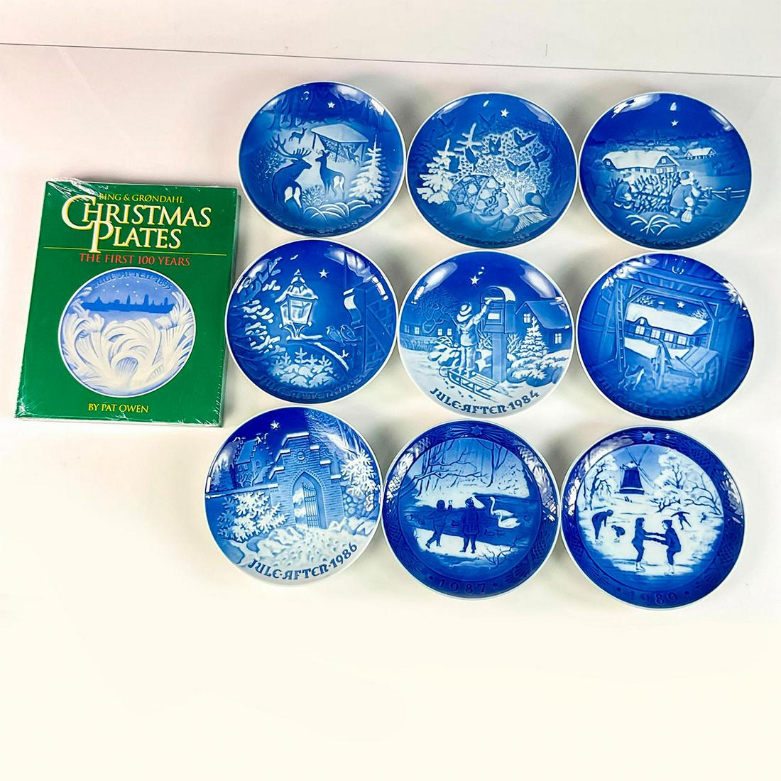 10pc Bing and Grondahl Christmas Plates and Book Set: Includes nine plates for the years: 1980-1987, and 1989. In blue and white coloration. Bing and Grondahl backstamp. Book is: 'Bing & Grondahl Christmas Plates, The First 100 Years', by Pat Owen, Landf