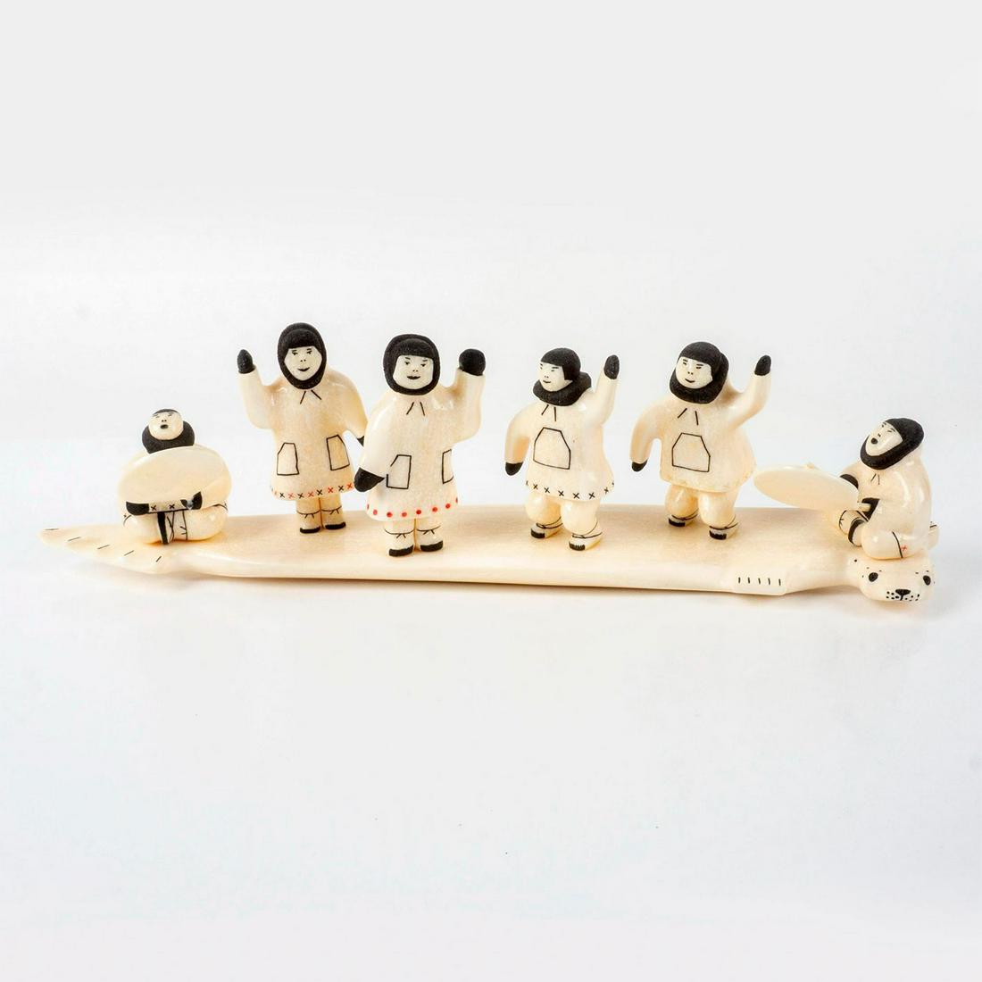 Signed Daniel K. Seetook Inuit Carved Bone Sculpture: Charming bone sculpture with six friendly figures waving and playing instruments while riding on the back of a seal. Black and red painted details. Artist signature, location, and number 99783 incised