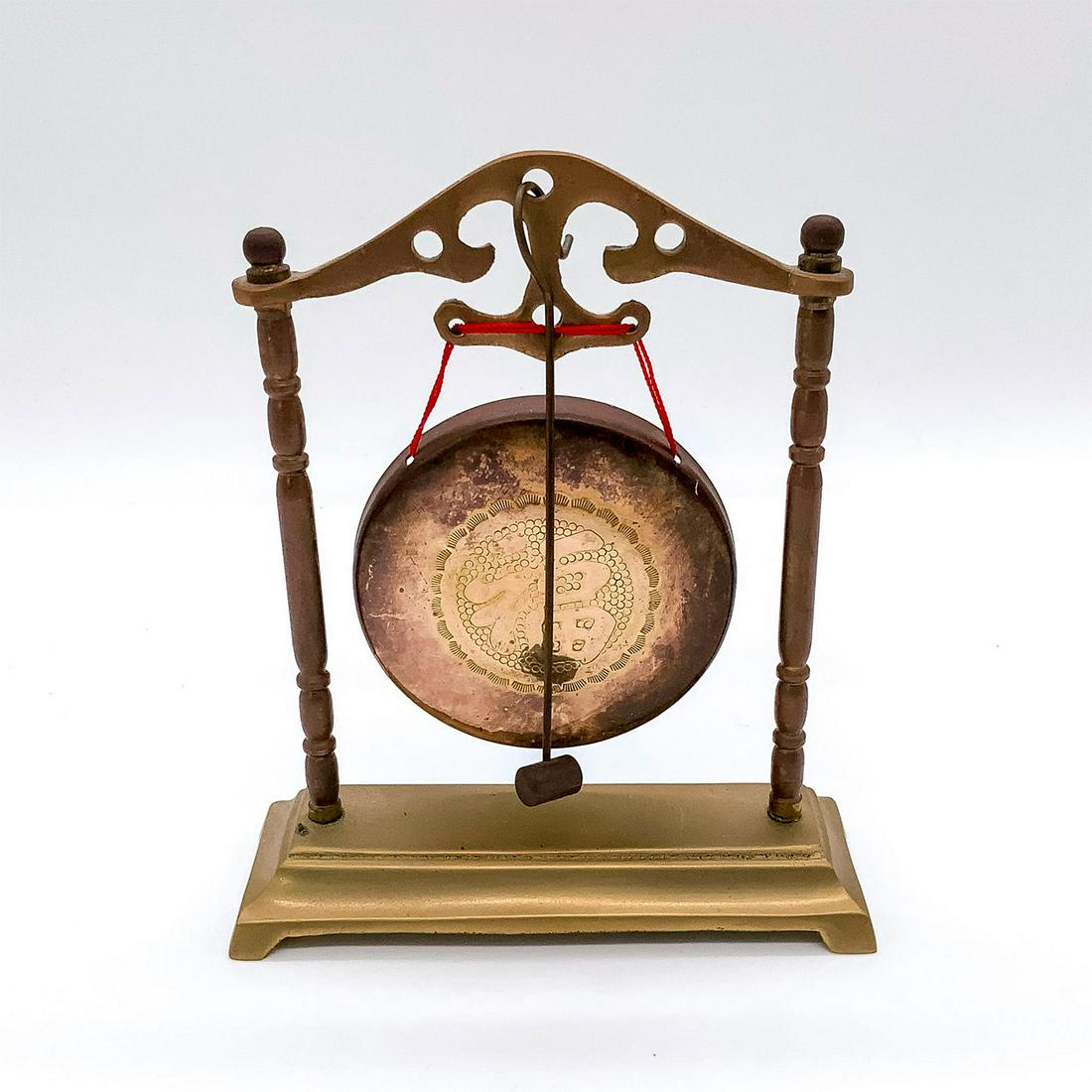 Chinese Small Brass Table Gong with Striker: Decorated with Chinese character design to center of gong. Striker attaches to gong. Dimensions: 5.25"L x 1.75"W x 6.25"H