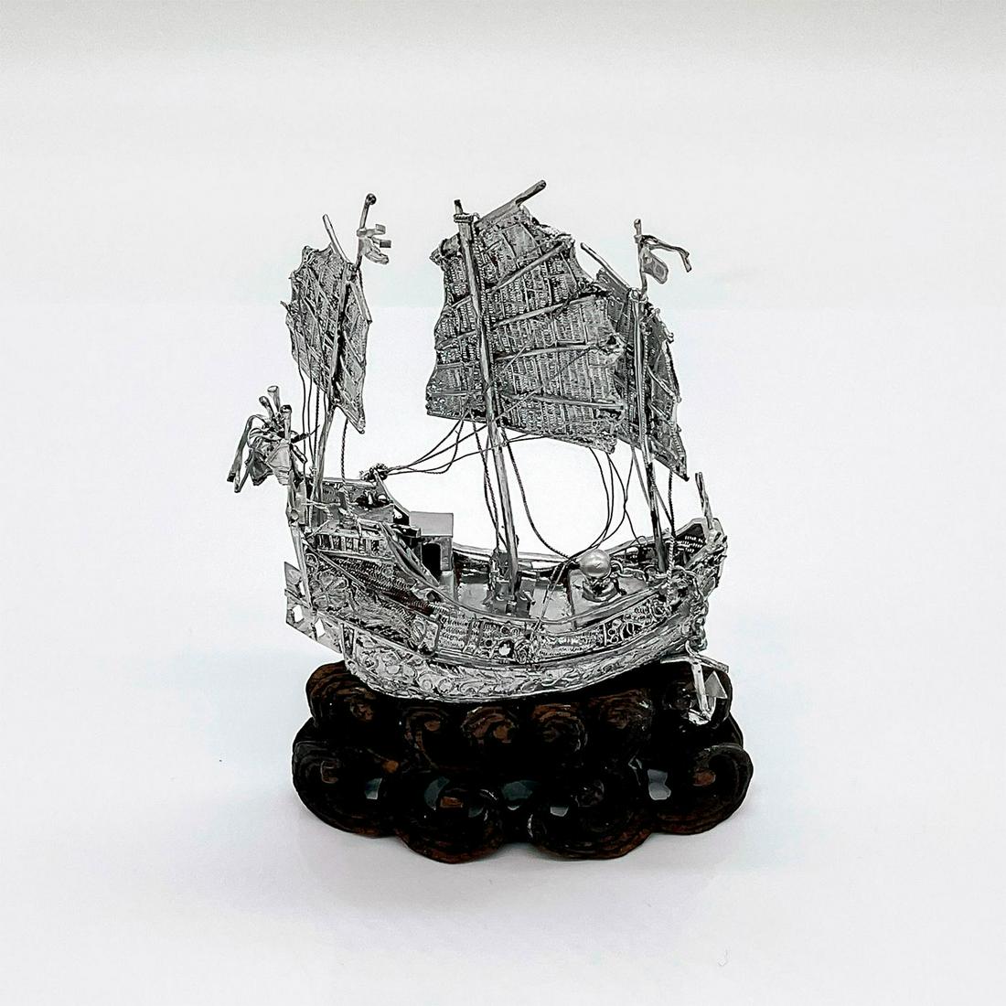 Chinese Silver Mini Model Figure of a Ship with Wooden Base: A miniature model figure of a Chinese junk ship attached to a carved wooden base. Dimensions: 2.5"L x 1"W x 3.75"H