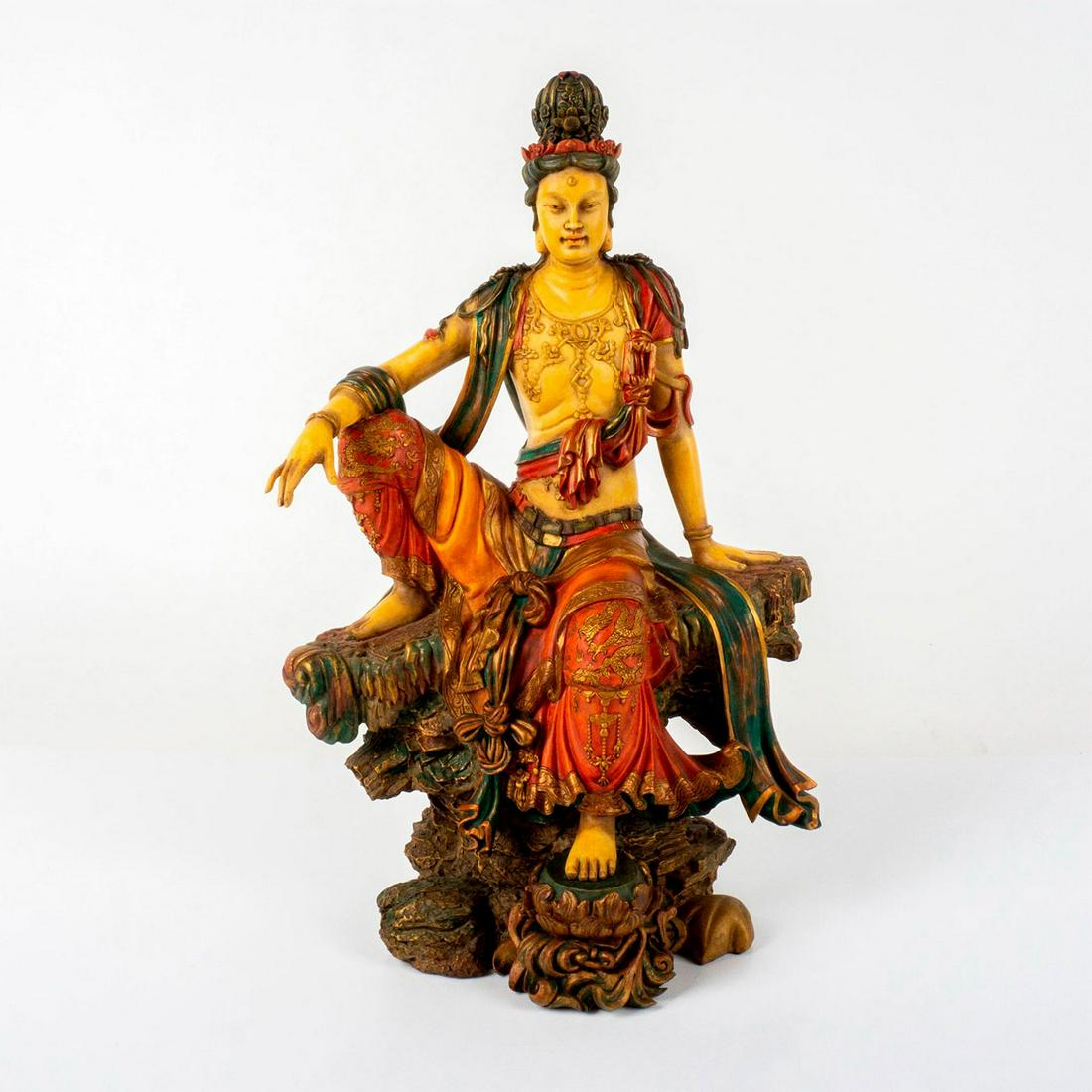 Summit Collection Statue, Kuan Yin: Large resin sculpture of Kuan Yin, the Chinese Buddhist goddess of mercy and compassion, seated in a variation of the pose of royal ease on a base imitating craggy rock with her right arm resting on h