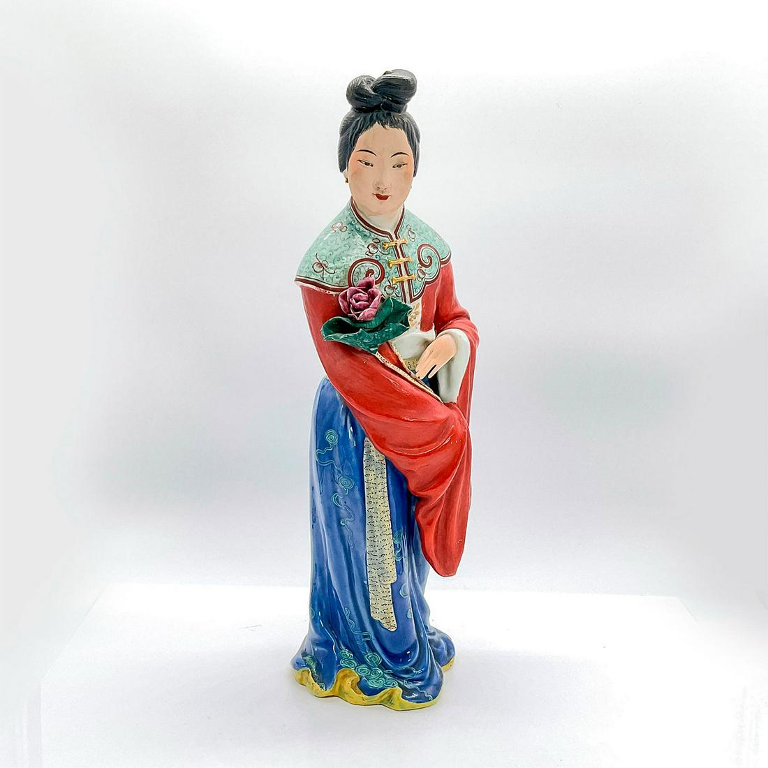 Chinese Figurine, Lady Holding Pink Flower: Vintage glazed ceramic figure of a standing lady in traditional red top with Guang sleeves and blue skirt holding a dark pink flower. Dimensions: 5.25"L x 4.25"W x 14.75"H Country of Origin: China