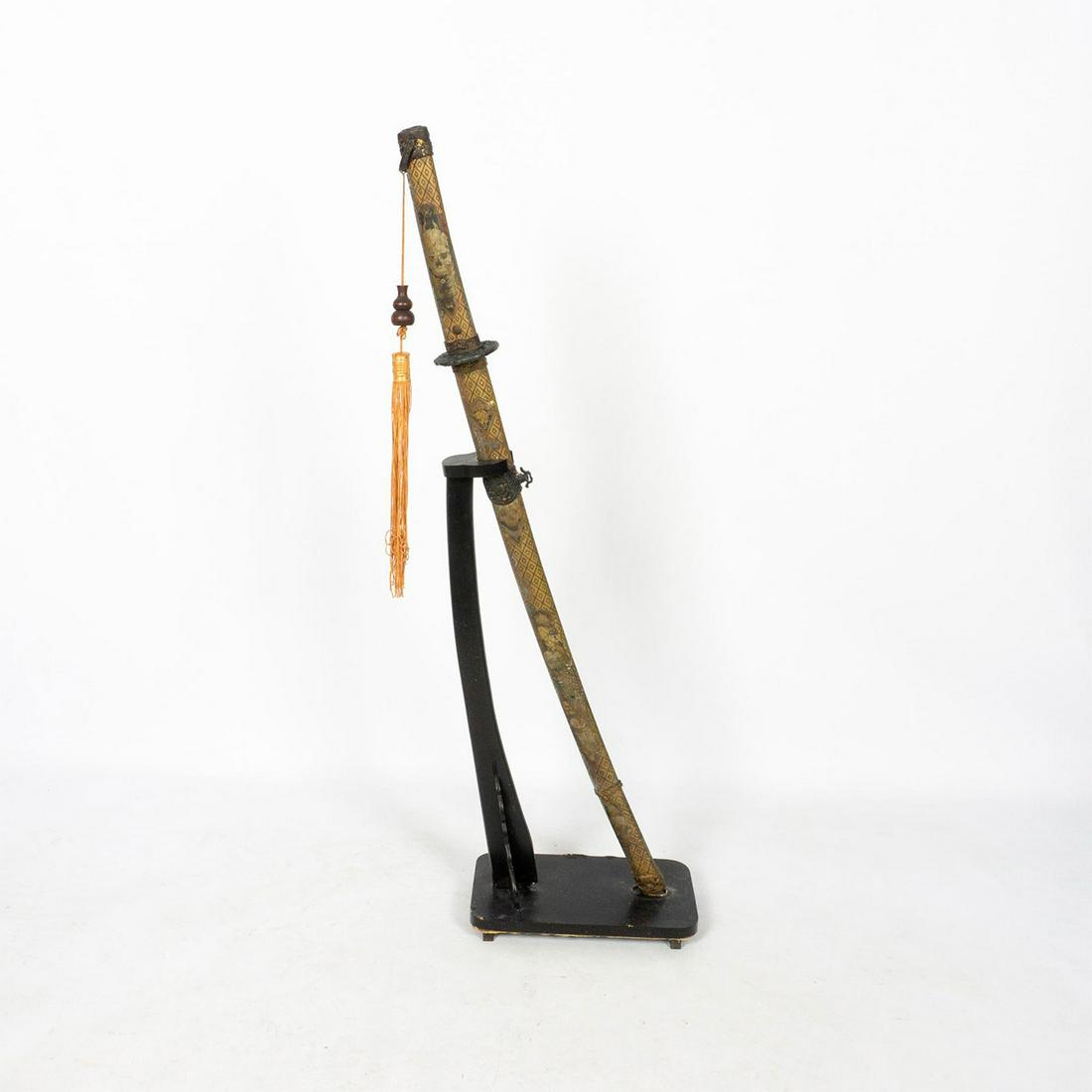 Japanese Steel Katana with Stand: 27.25in carbon steel blade with composite saya and tsuka adorn with demons, skulls, and ghouls. A wooden lucky gourd bead on a tawny-brown tassel. Includes a wooden stand. Measurements of katana in sa