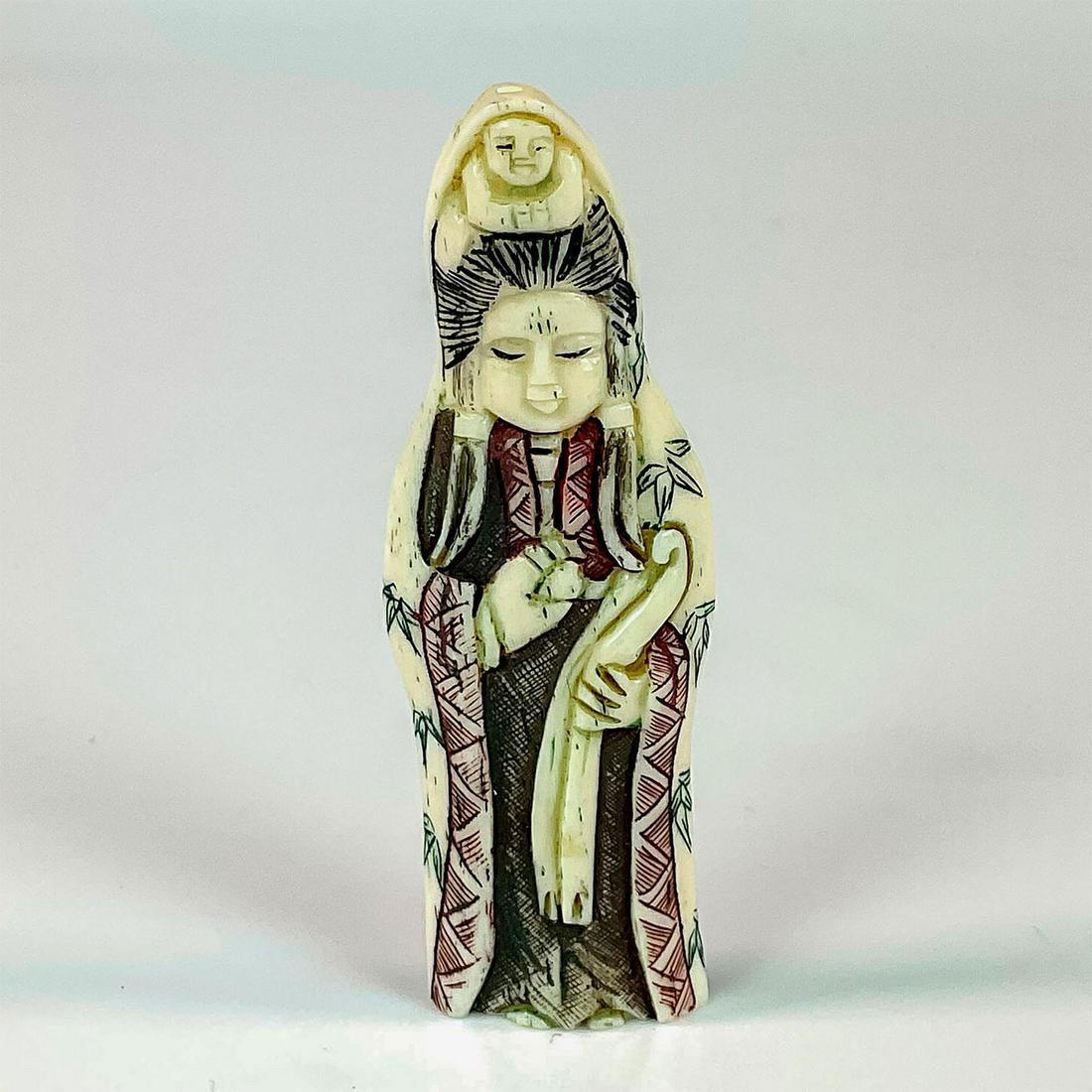 Japanese Small Carved Bone Guanyin Netsuke Figurine: A flat figure of the Guanyin with a child. The Bodhisattva adorn with green bamboo leaves adorned on her robed. Japanese characters markings on the back. Dimensions: 1.25"L x 0.25"W x 3.5"H Country of