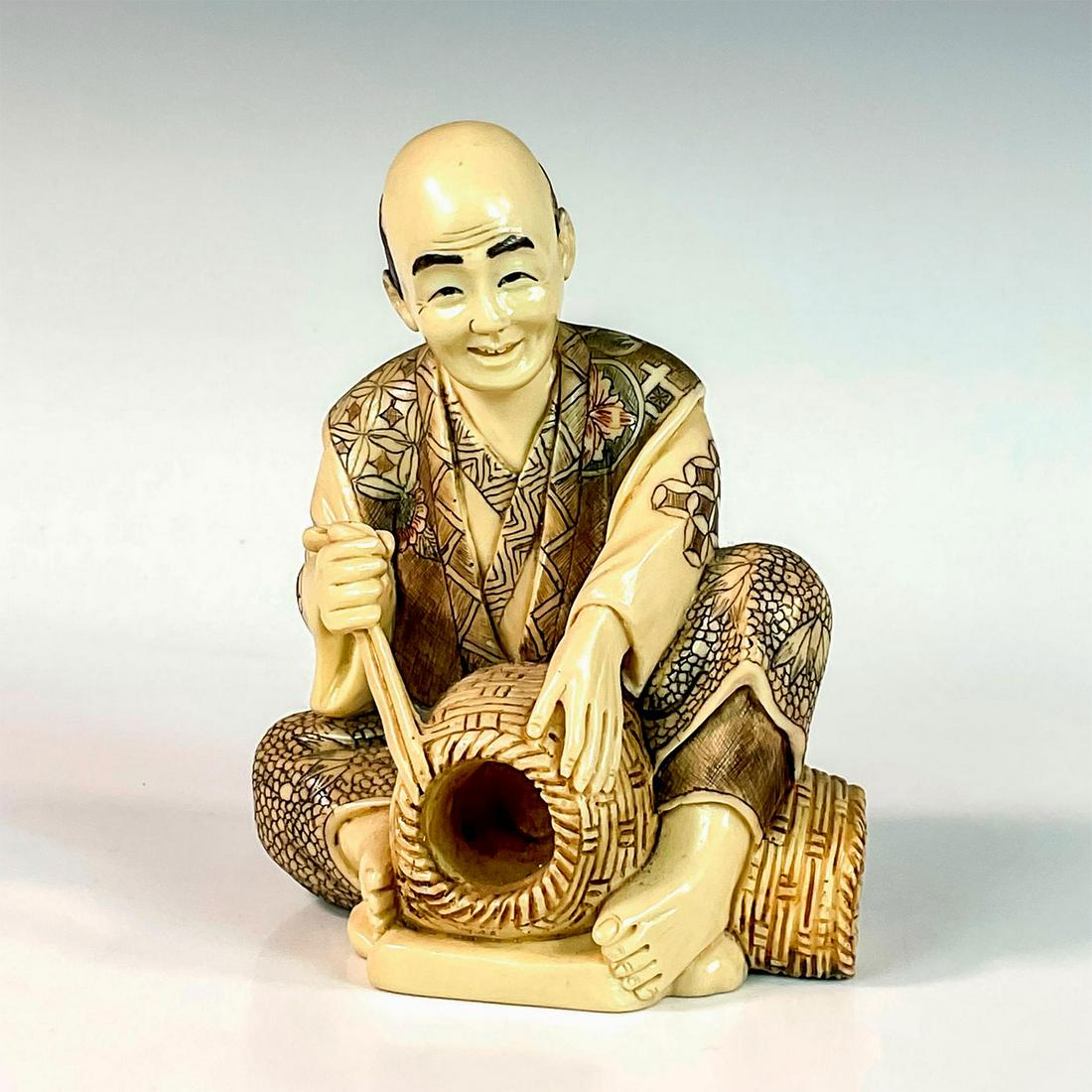 Japanese Inked Resin Figure of a Basket Weaver: A figure of a man weaving a basket. He is dressed in a beautiful detailed floral attire. Japanese character marks on the base. Dimensions: 4.75"L x 4"W x 6"H Country of Origin: Japan