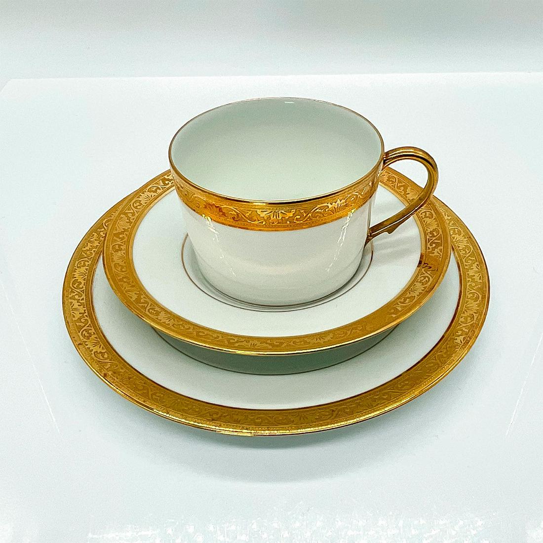 Raynaud Ceralene Limoges Tea Trio, Ambassador Gold: Tea cup, saucer and sandwich plate in white porcelain with ornate gold rim. Tea cup 4.25"L x 3.5"W x 2.25"H. The sandwich plate is 7.5" diameter. Issued: 20th c.