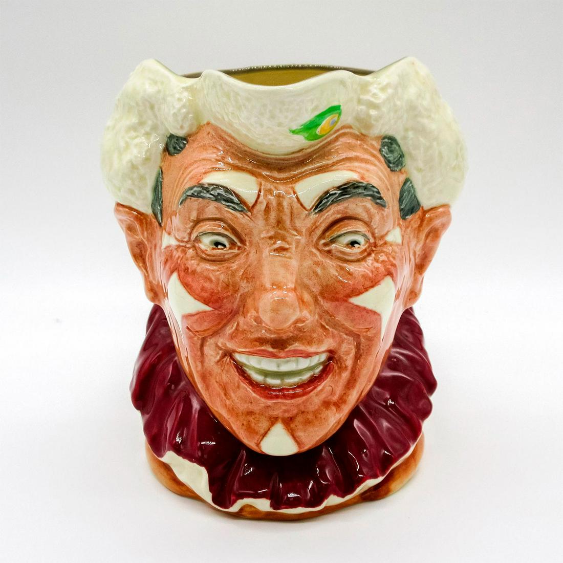 The Clown - Large - Royal Doulton Character Jug: Variation three; white hair and burgundy collar. Multicolored handle. Royal Doulton backstamp. Issued: 1951-1955 Dimensions: 3.25" H Manufacturer: Royal Doulton Country of Origin: England