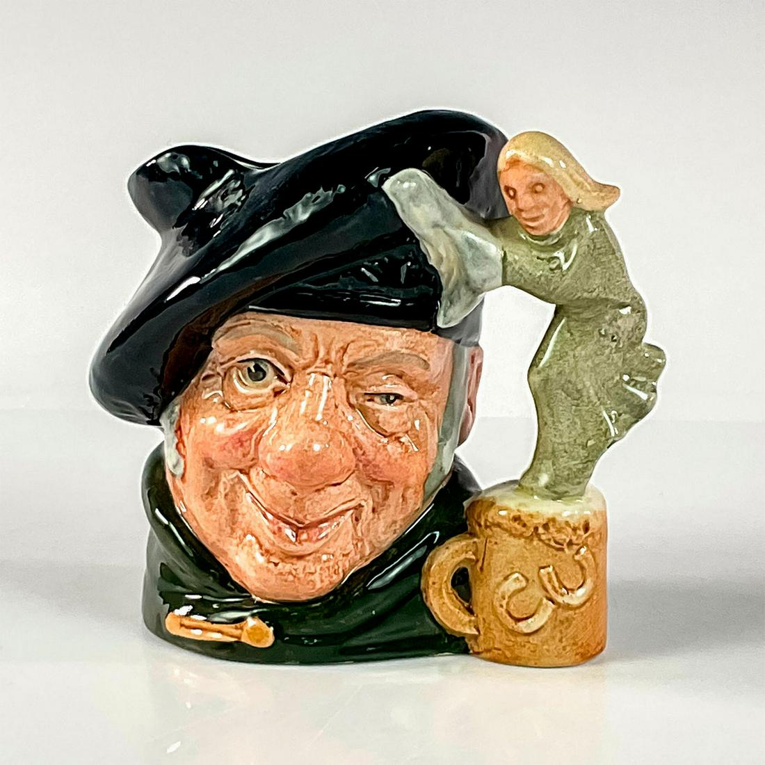 Tam O Shanter D6636 - Small - Royal Doulton Character Jug: Dark blue tam; green cloak. In a poem written by Robert Burns in 1791, Tam O' Shanter is a drunken farmer who happens upon witches who pursue him and his horse. He escapes, but his horse doesn't quite