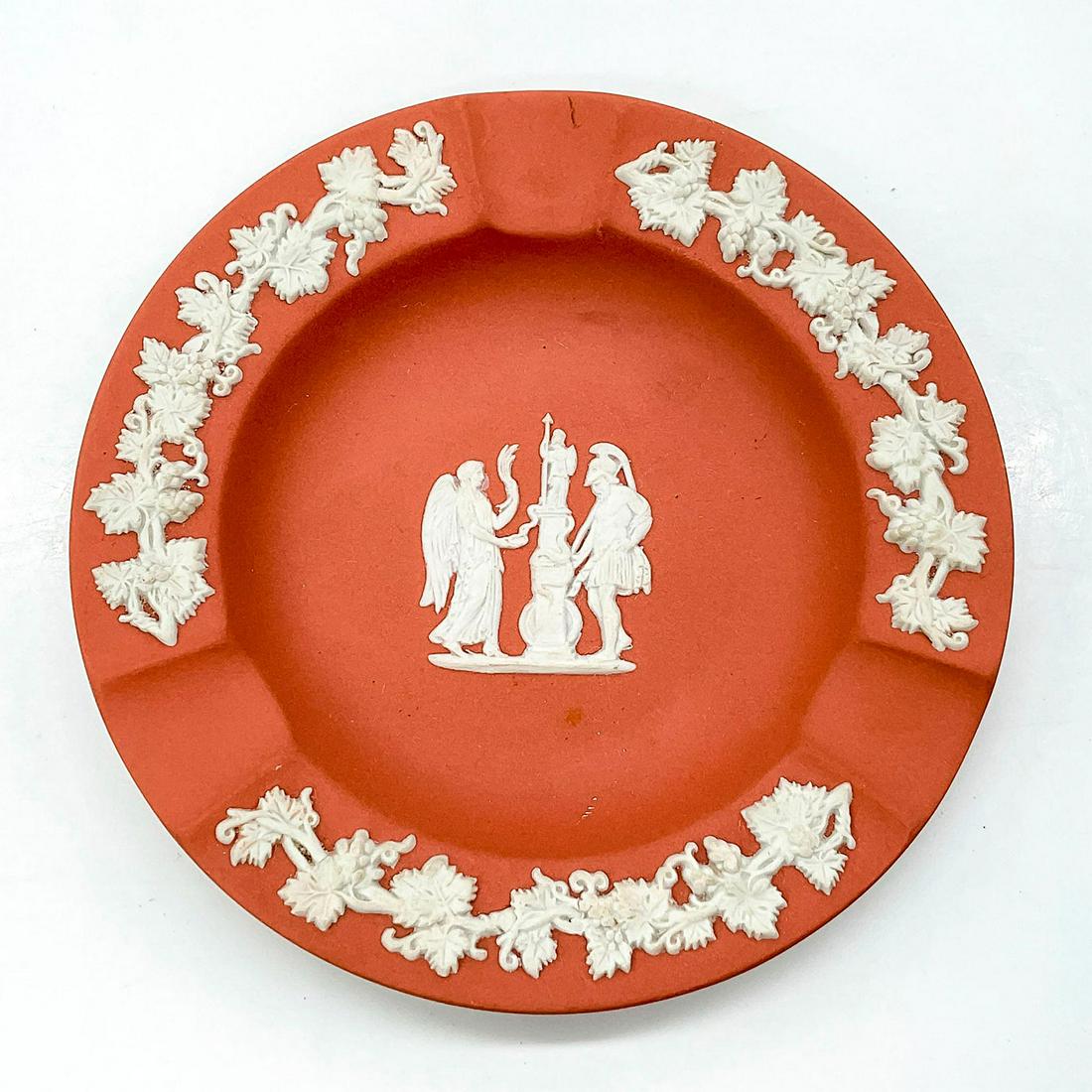 Wedgwood Pink Jasperware Trojan Ashtray: Rose pink matte finish ashtray with three cigarette slots; white grapevine and trojan sprigging designs. Wedgwood backstamp. Issued: 20th c. Dimensions: 0.5"H x 4.25"Dia. Manufacturer: Wedgwood Countr