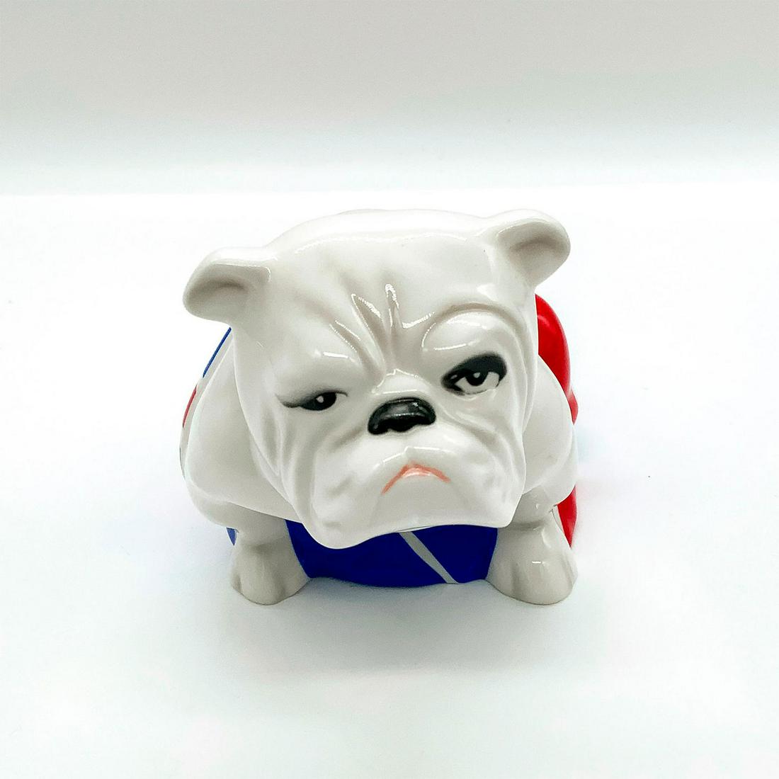 Royal Doulton Bulldog Figure, Skyfall Jack DD007: Glossy finish. White seated bulldog with Union Jack flag. Appeared in the 2012 James Bond film Skyfall. Royal Doulton and Skyfall backstamp. Bone china. Issued: 2012 Dimensions: 6"L x 3.25"W x 3.75"H 
