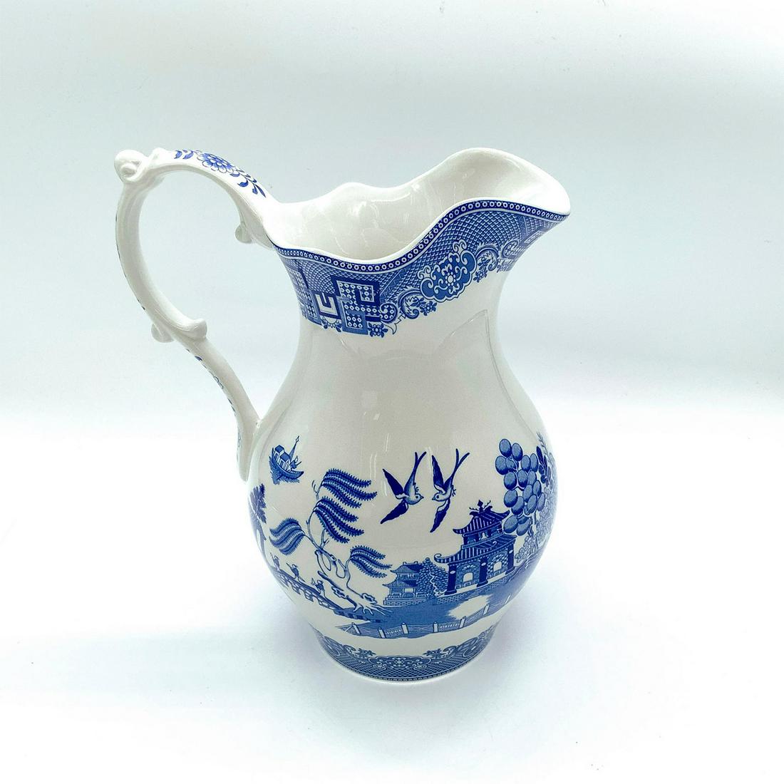 Spode Ewer, Blue Willow: Beautiful depiction of Asian seaside village scene with geometric and floral pattern to rim, handle, and bottom. Spode backstamp. This item has its original box with dimensions: 11 in. L x 7.25 in. W 