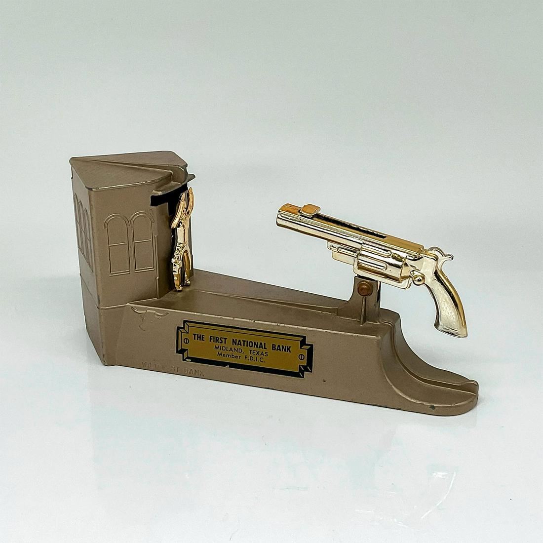 First National Bank Midland Texas Wild West Toy Bank: The cast metal bank features a cowboy standing in front of a saloon. Put a coin on the barrel of the gun and pull the spring-loaded trigger. If you shoot the coin into the slot, you'll knock the cowbo
