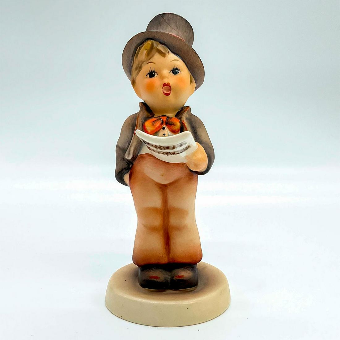 Goebel Hummel Figurine, Street Singer: Porcelain hand painted in matte finish. Goebel backstamp. Impressed M. I. Hummel to round base. This item has no reserve. Artist: M. I. Hummel Issued: 20th c. Dimensions: 1.75"W x 5.25"H x 2.25"Dia. M