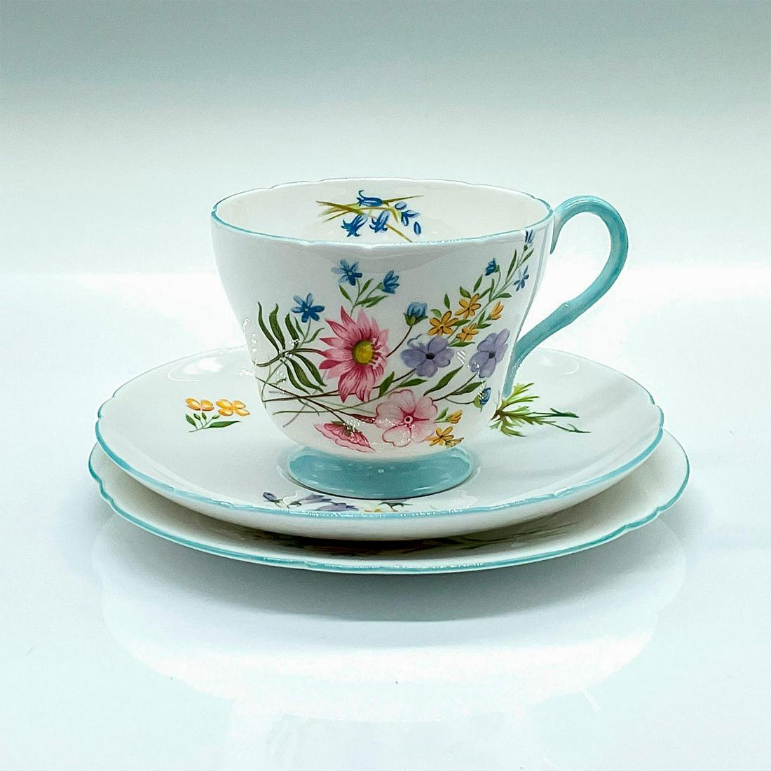 3pc Shelley Fine Bone China Cup and Saucers, Wild Flowers: White ground adorn with Gainsborough wildflowers and blue trims. Includes teacup, saucer, and snack plate. Shelley backstamps. Tea cup: 4"L x 3.25"W x 2.75"H. Saucer: 0.75"H x 5.5"dia. Snack plate: 0.
