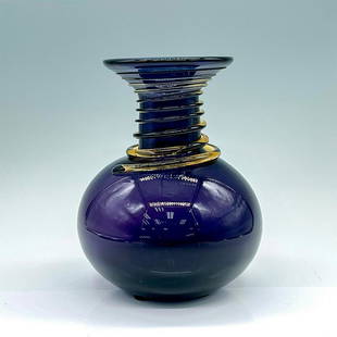 Blenko Glass Company Purple Vase: A beautiful amethyst-purple hand-blown vessel adorn with an amber-yellow glass coil around the neck. Blenko Glass sticker on the base. Dimensions: 5.5"W x 7"H Country of Origin: United States Manufact