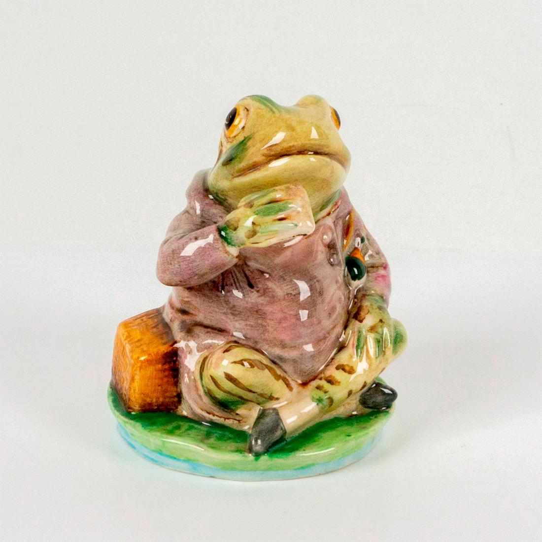 Beswick Beatrix Potter's Figurine, Mr. Jeremy Fisher: Depicts a frog wearing a pink jacket sitting on top of a lily pad with one arm raised. Beswick backstamp. Dimensions: 2.5"L x 2.5"W x 3"H Manufacturer: Beatrix Potter Country of Origin: England
