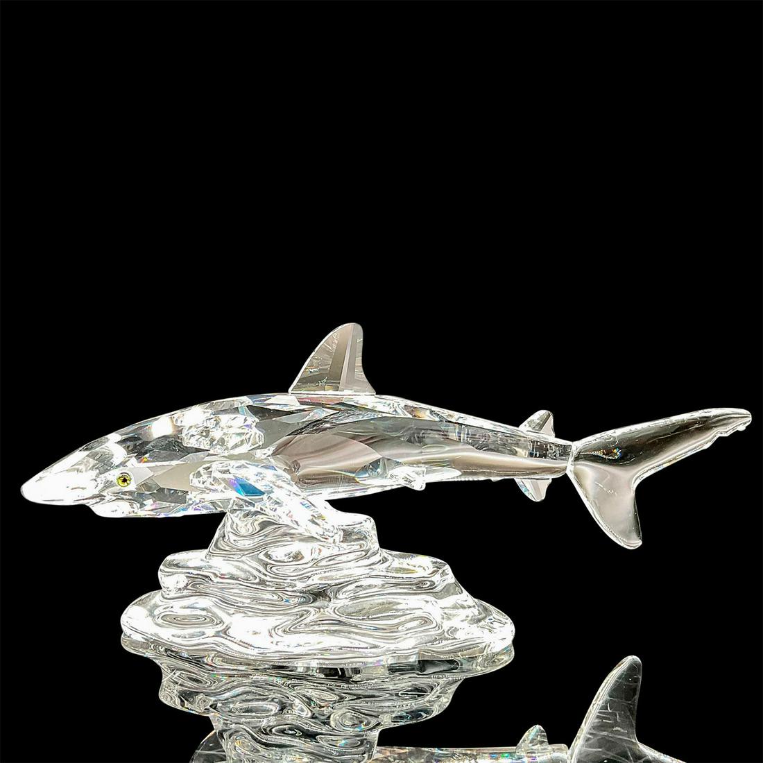 Swarovski Silver Crystal Figurine, Shark: A clear faceted shark swimming over a clear rocky base. Swarovski mark. This item has its original box: 6"W x 4.75"H Artist: Anton Hirzinger Issued: 2001-2004 Dimensions: 5"L x 2.5"W x 2"H Manufacture