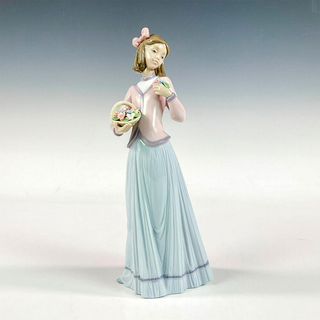 Innocence In Bloom 1007644 - Lladro Porcelain Figurine: Glossy finish; Lladro backstamp. Artist: Jose Puche Issued: 1996 - 1996 Dimensions: 9.75"H x 4.25"W Manufacturer: Lladro Country of Origin: Spain
