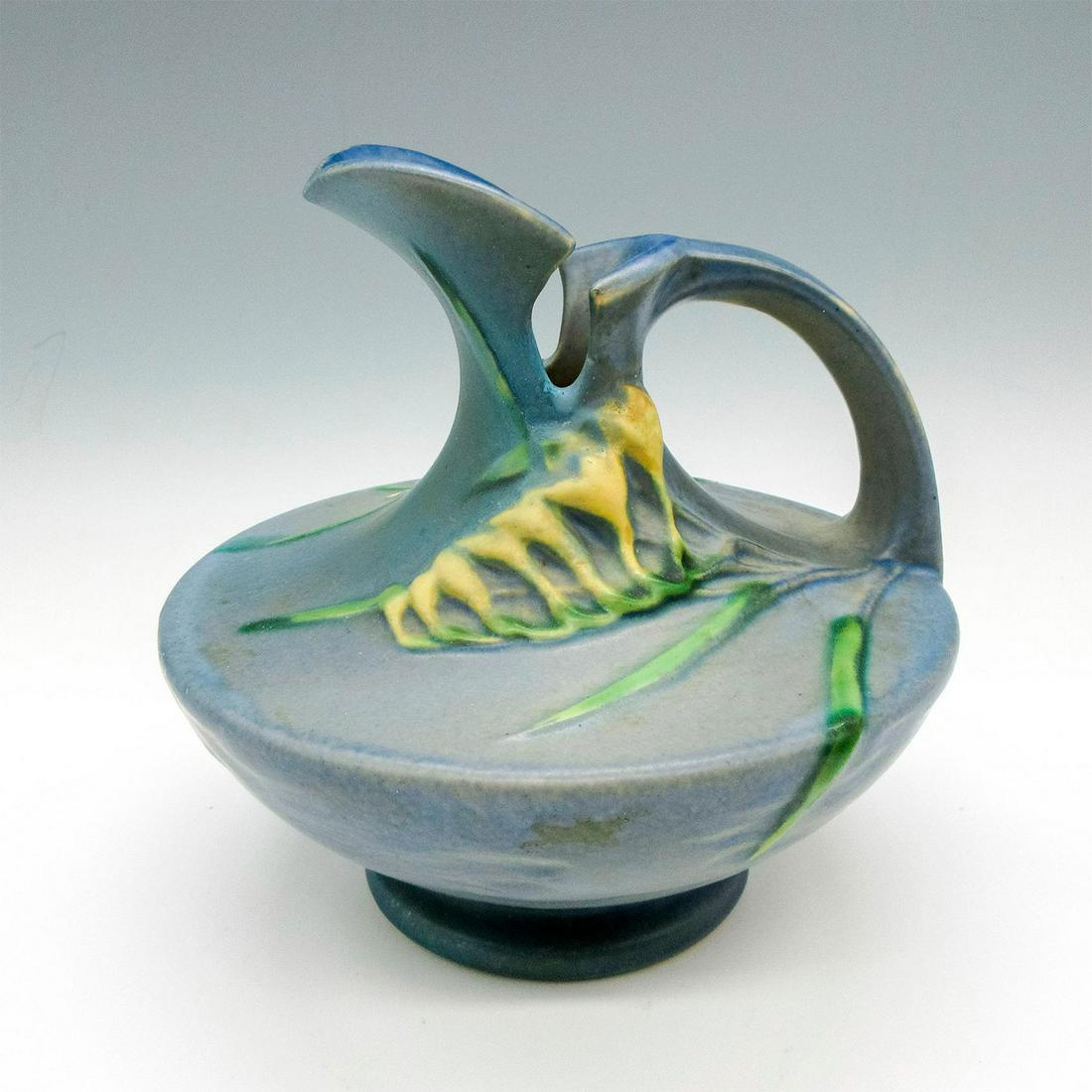 Rosemary Pottery Pitcher, Freesia: Glazed finish over blue with yellow colored floral design. Roseville Pottery raised mark. 19. Issued: c.1938 Dimensions: 6.5"L x 6.5"W x 6"H Manufacturer: Roseville Pottery Country of Origin: United S