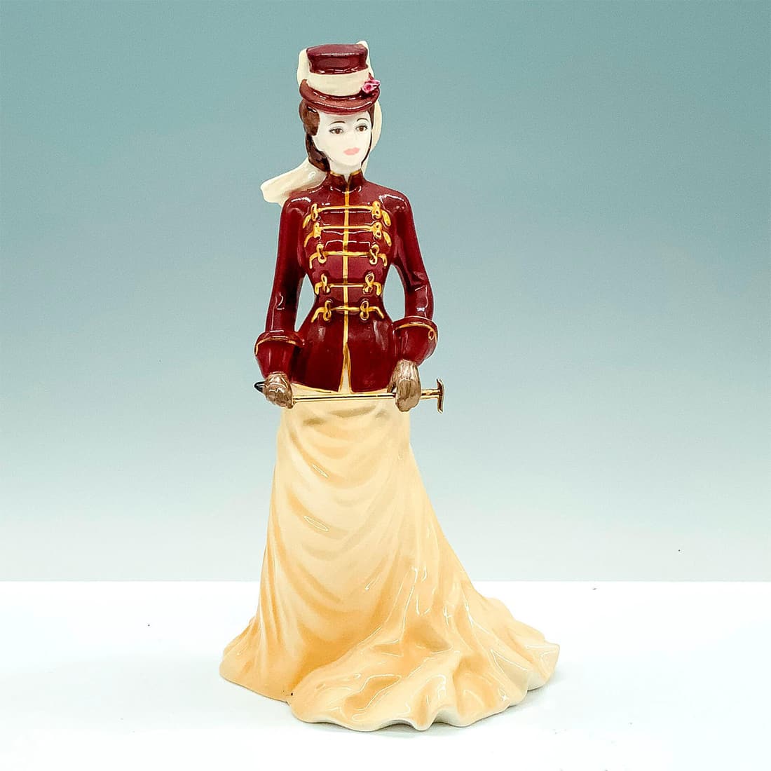 Coalport Bone China Figurine, The Rider: A commissioned Home Shopping limited edition figure that depicts a woman wearing a yellow dress and red jacket and hat while holding a gold-colored cane. Coalport backstamp. Artist: Jack Glynn Issued: