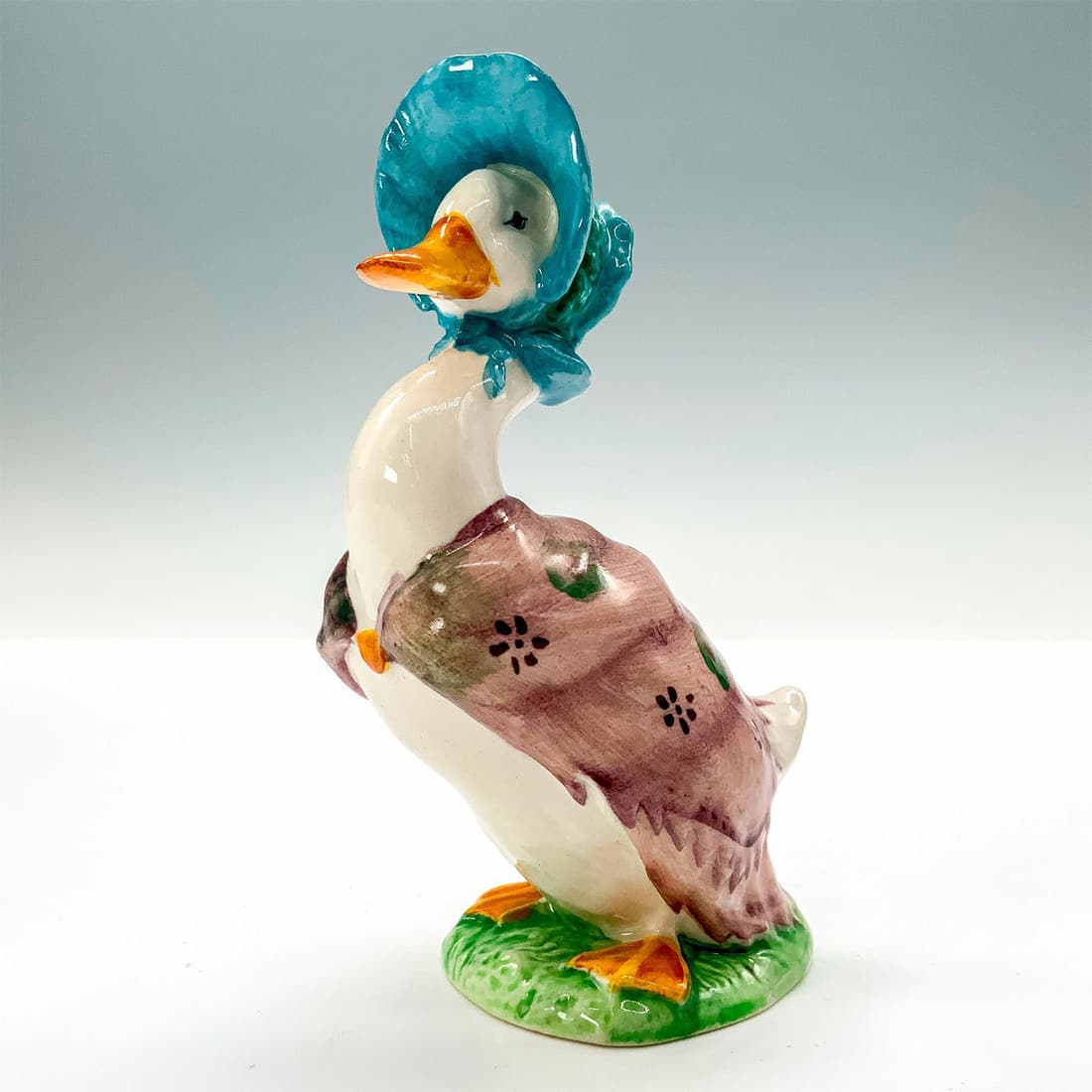 Beatrix Potter's Figurine, Jemima Puddleduck: A figurine depicting a white mother duck dressed in floral scarf and blue bonnet. Beatrix Potter backstamp. Dimensions: 1.5"L x 3"W x 4.25"H Manufacturer: Beatrix Potter Country of Origin: England