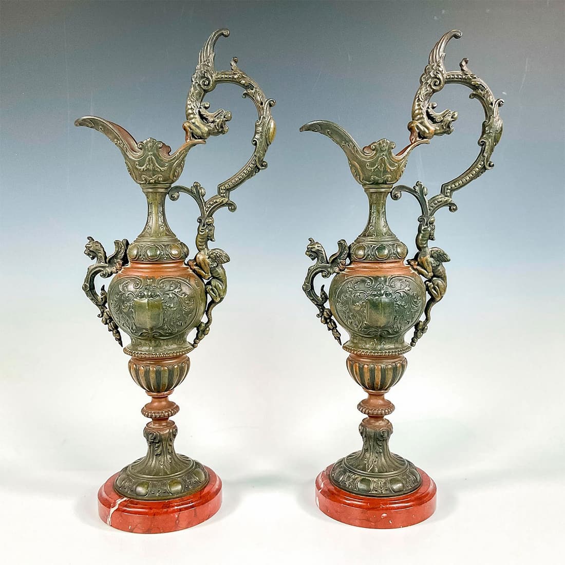 Pair of Renaissance Revival Dragon Ewer Sculptures: Two magnificent neo-renaissance sculpturesque ewers with dragon decoration. The pitcher rests on a marble base. Issued: c. 1890 Dimensions: 8.25"L x 5.25"W x 20"H