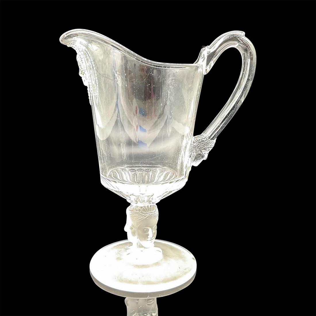 George Duncan Glass Three Face Creamer: A tall clear glass creamer decorated with faces at neck and handle. Frosted glass stem embossed with three faces. Issued: c. 1950 Dimensions: 5”L x 3.5”W x 7.25”H Manufacturer: Georg
