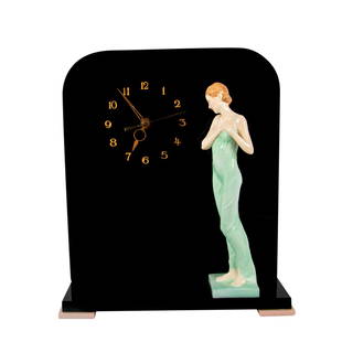 Celia HN1727 Clock - Royal Doulton Art Deco Figurine Display: A clock with a glossy black finish and gilded numbers and hands. A figure of a woman in a pale green dress attached to the base. Artist: Leslie Harradine Dimensions: 13"L x 4.5"W x 14.75"H Manufacture