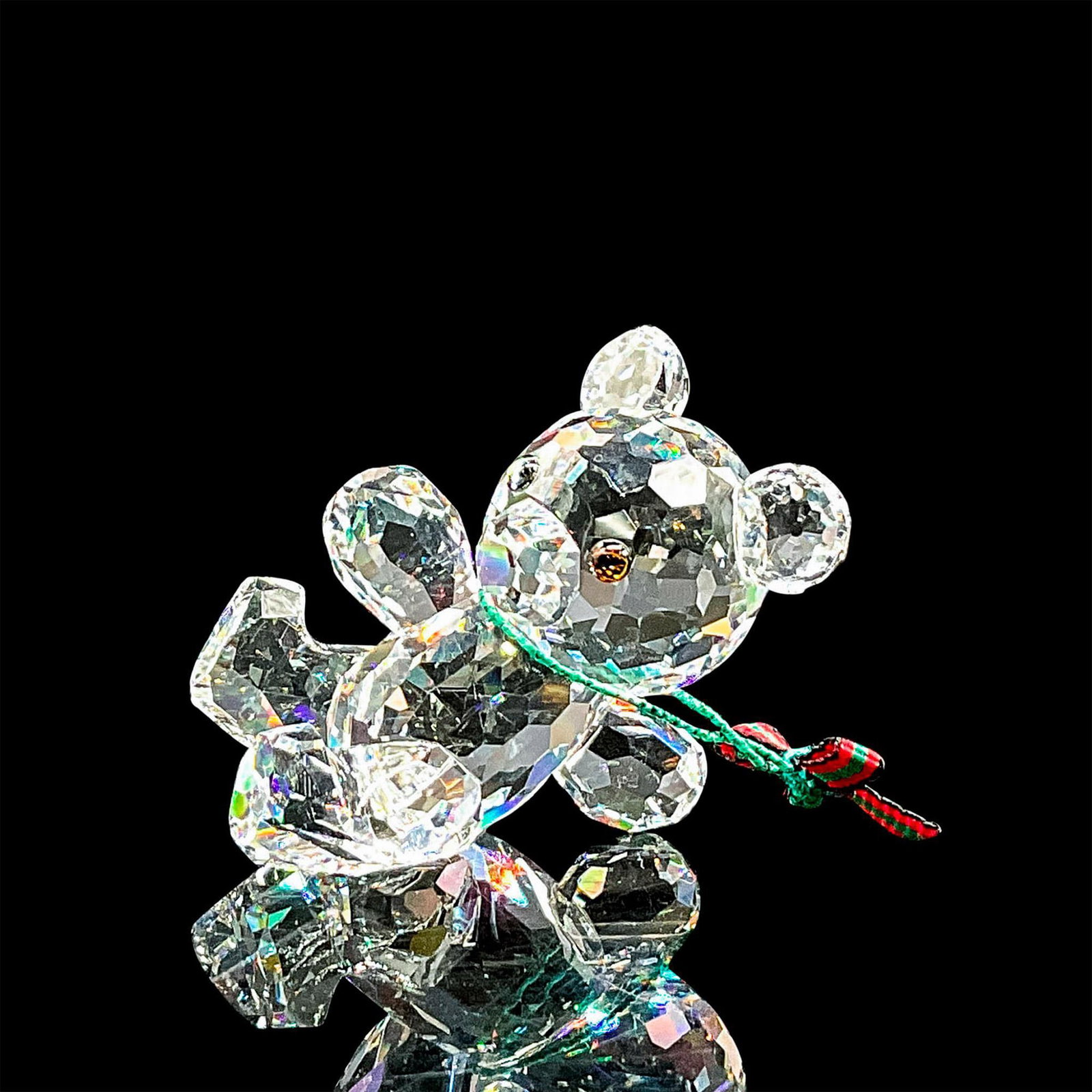 Holiday Kris Bear Leaning Back - Swarovski Crystal Figurine: Brilliant clear crystal Kris Bear holding a satin jar with a gold bee. Swarovski etched backstamp. Includes original box 3.75"H x 3.25"dia. Dimensions: 2"L x 1.5"W x 1.25"H Manufacturer: Swarovski Cou