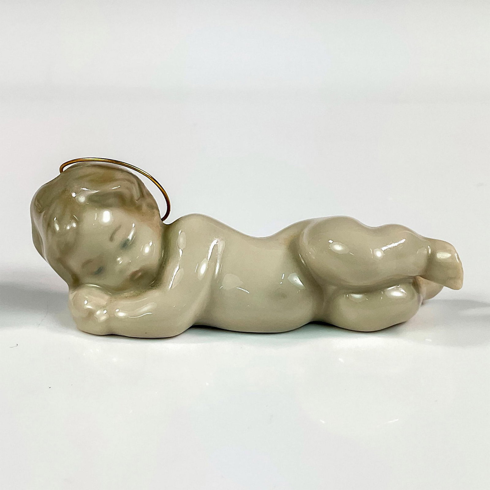 Baby Jesus 1004535 - Lladro Porcelain Figurine: Glossy finish; Lladro backstamp. Artist: Fulgencio Garcia Issued: 1971 Dimensions: 1.25"H x 3.5"W Manufacturer: Lladro Country of Origin: Spain
