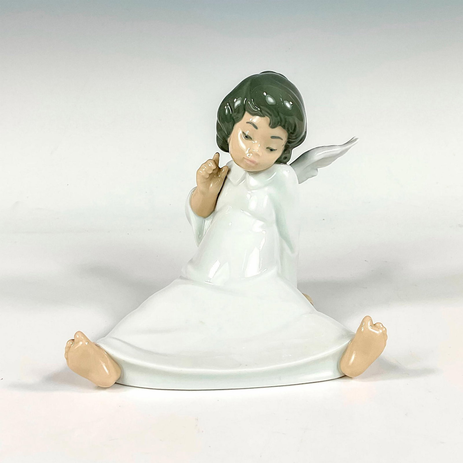 Cherub, Wondering 1004962 - Lladro Porcelain Figurine: Glossy finish; Lladro backstamp. Artist: Salvador Debon Issued: 1977 - 2017 Dimensions: 5.5"H x 6.25"W Manufacturer: Lladro Country of Origin: Spain