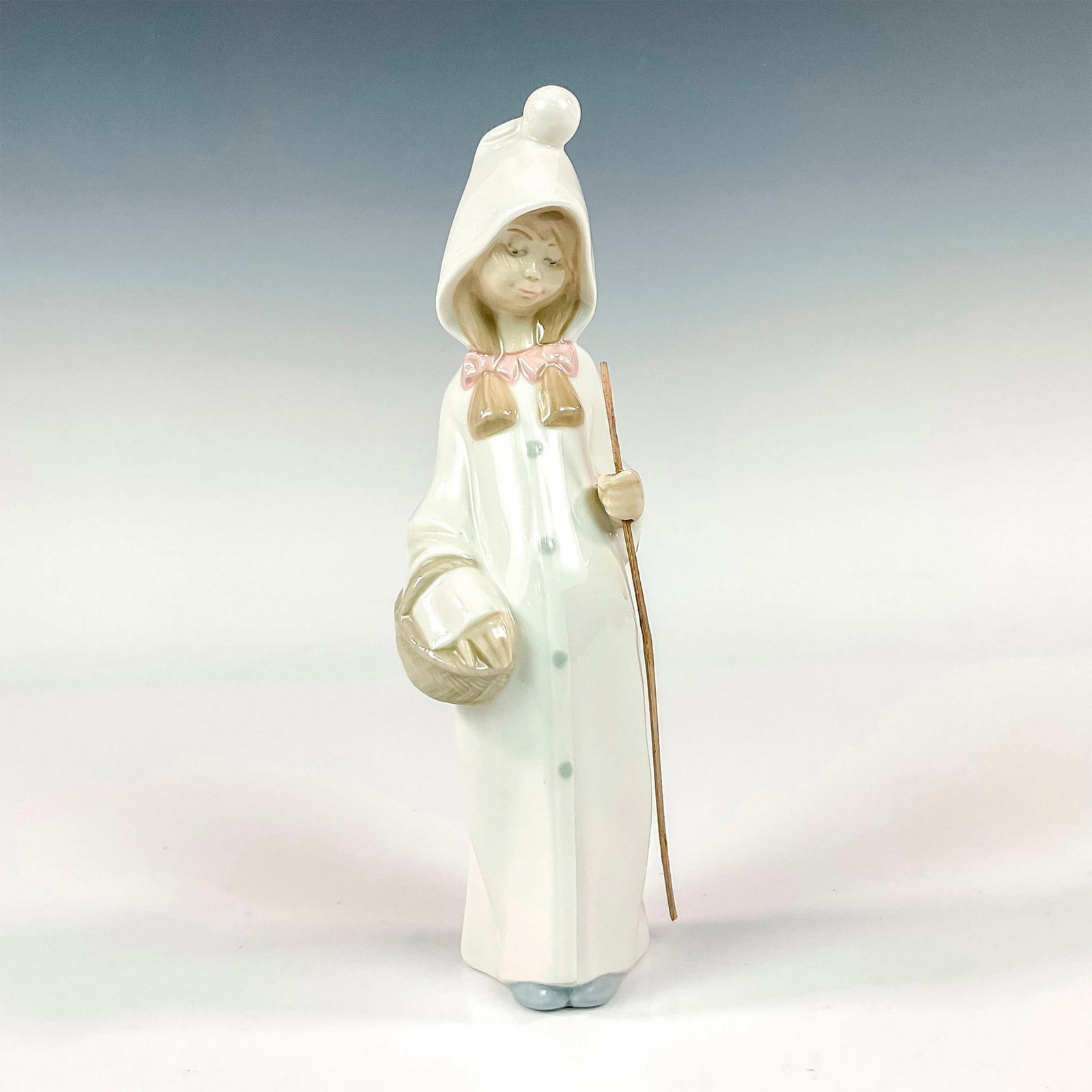 Girl With Basket 100678 - Lladro Porcelain Figurine: Glossy finish modeled as a young girl carrying a basket with her stick in hand. Lladro backstamp. Artist: Juan Huerta Issued: 1969-2001 Dimensions: 2.5"L x 2"W x 8.75"H Manufacturer: Lladro Country o