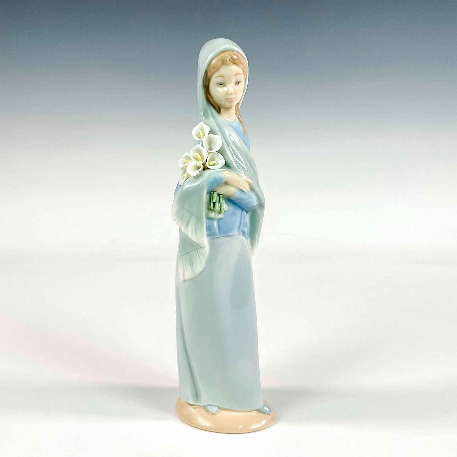 Girl With Calla Lilies 1004650 - Lladro Porcelain Figurine: Glossy finish; Lladro backstamp. Artist: Vicente Martinez Issued: 1969 - 1998 Dimensions: 9"H x 2.75"W Manufacturer: Lladro Country of Origin: Spain