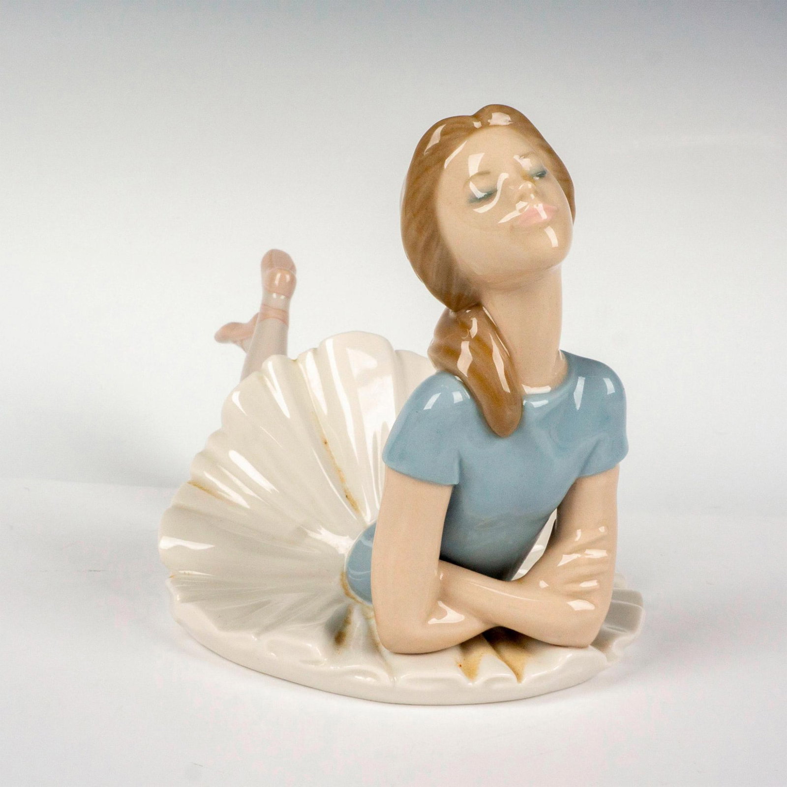 Heather 1001359 - Lladro Porcelain Figurine: Glossy finish modeled as a resting ballerina in soft pastel colors. Lladro backstamp. Artist: Juan Huerta Issued: 1978-1993 Dimensions: 4.5"L x 9"W x 5"H Manufacturer: Lladro Country of Origin: S