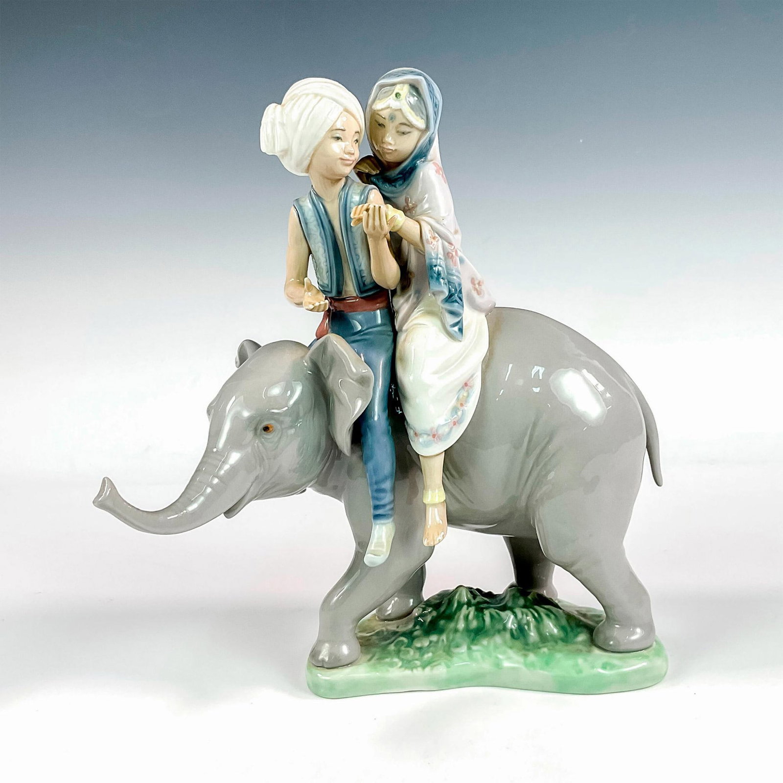Hindu Children 1005352 - Lladro Porcelain Figurine: Glossy finish; Lladro backstamp. Artist: Jose Puche Issued: 1986 Dimensions: 9"H x 7.5"W Manufacturer: Lladro Country of Origin: Spain